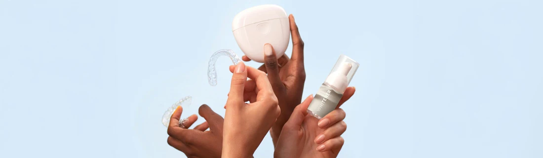 four hands hold up four different cosmetic dentistry items against a light blue background