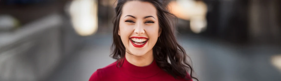 a woman in a red sweater and red lipstick is smiling happily at the viewer